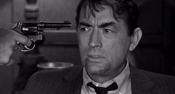 Movie still from “Mirage” (1965), directed by Edward Dmytryk – Black and white photograph of a man holding a gun; Close Up shot, Over the shoulder angle