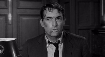 Movie still from “Mirage” (1965), directed by Edward Dmytryk – Black and white photograph of a man wearing a suit and tie; Close Up shot, Over the shoulder angle