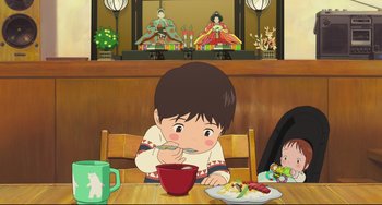 Movie still from “Mirai” (2018), directed by Mamoru Hosoda – A child eating a bowl of food at a table; Medium shot, High angle