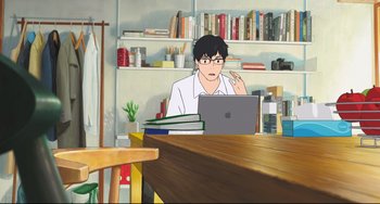 Movie still from “Mirai” (2018), directed by Mamoru Hosoda – A man sitting in front of a computer in a room; Wide shot, Over the shoulder angle