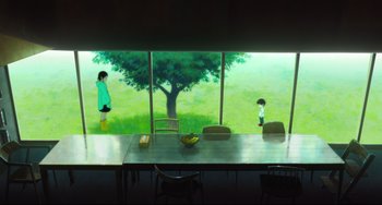 Movie still from “Mirai” (2018), directed by Mamoru Hosoda – Two children are standing at a table in front of a large window; Extreme Wide shot, Low angle