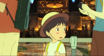 Movie still from “Mirai” (2018), directed by Mamoru Hosoda – A boy with a hat and suspenders is standing in front of an audience; Close Up shot, High angle