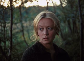 Movie still from “Mirror” (1975), directed by Andrei Tarkovsky – A woman with blonde hair is standing in the woods; Close Up shot, Over the shoulder angle