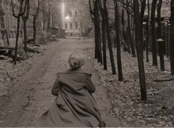 Movie still from “Mirror” (1975), directed by Andrei Tarkovsky – An old photo of a woman walking down a path in the woods; Wide shot, High angle