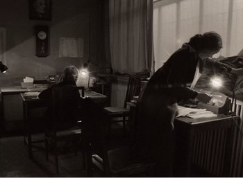 Movie still from “Mirror” (1975), directed by Andrei Tarkovsky – A woman standing at a desk in front of a window; Wide shot, High angle
