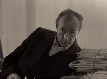 Movie still from “Mirror” (1975), directed by Andrei Tarkovsky – An old photo of a man with a bunch of papers; Close Up shot, High angle