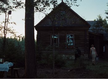 Movie still from “Mirror” (1975), directed by Andrei Tarkovsky – Two people standing in front of an old log cabin; Extreme Wide shot, Low angle