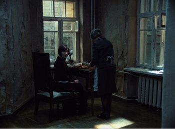 Movie still from “Mirror” (1975), directed by Andrei Tarkovsky – A woman standing at a wooden table with a man; Wide shot, High angle