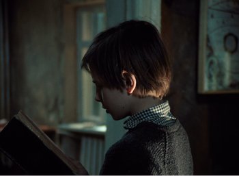 Movie still from “Mirror” (1975), directed by Andrei Tarkovsky – A young boy is looking at something in the dark; Medium shot, Over the shoulder angle