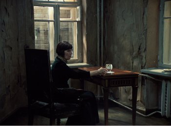 Movie still from “Mirror” (1975), directed by Andrei Tarkovsky – A woman sitting at a table with a glass of wine; Wide shot, Over the shoulder angle