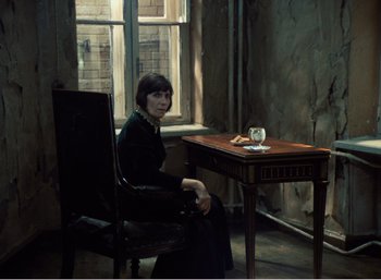 Movie still from “Mirror” (1975), directed by Andrei Tarkovsky – A woman sitting at a table in a dark room; Medium shot, High angle