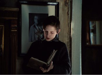 Movie still from “Mirror” (1975), directed by Andrei Tarkovsky – A young boy is reading a book in a room; Medium shot, Over the shoulder angle