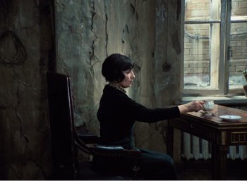 Movie still from “Mirror” (1975), directed by Andrei Tarkovsky – A woman sitting at a table with a cup of coffee; Medium shot, High angle