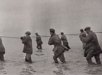 Movie still from “Mirror” (1975), directed by Andrei Tarkovsky – A black and white photo of a group of men in the water; Wide shot, Low angle