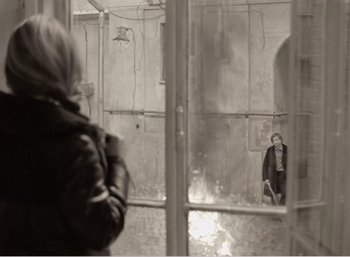 Movie still from “Mirror” (1975), directed by Andrei Tarkovsky – A woman standing in front of a mirror in a room; Wide shot, Over the shoulder angle