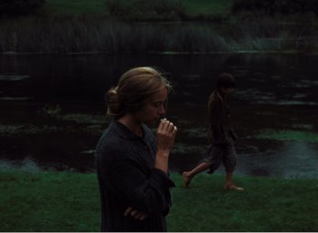 Movie still from “Mirror” (1975), directed by Andrei Tarkovsky – A woman standing next to a man near a body of water; Wide shot, Over the shoulder angle