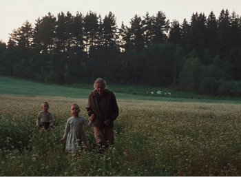 Movie still from “Mirror” (1975), directed by Andrei Tarkovsky – A man and two children walking through a field of flowers; Wide shot, Low angle