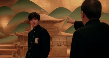 Movie still from “Mishima: A Life in Four Chapters” (1985), directed by Paul Schrader – A man pointing at a man wearing a black jacket; Medium shot, Over the shoulder angle