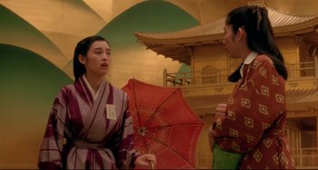 Movie still from “Mishima: A Life in Four Chapters” (1985), directed by Paul Schrader – Two women in traditional japanese garb holding an umbrella; Medium shot, Low angle