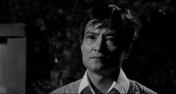Movie still from “Mishima: A Life in Four Chapters” (1985), directed by Paul Schrader – Black and white photograph of a man in a sweater; Close Up shot, Low angle
