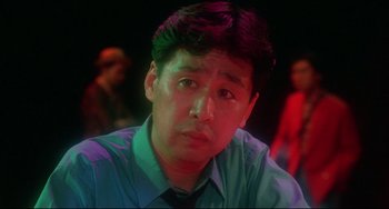 Movie still from “Mishima: A Life in Four Chapters” (1985), directed by Paul Schrader – A person wearing a shirt and a tie; Close Up shot, Low angle