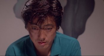 Movie still from “Mishima: A Life in Four Chapters” (1985), directed by Paul Schrader – A person wearing a blue shirt; Close Up shot, Low angle