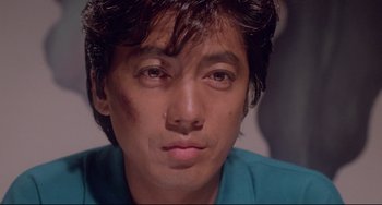 Movie still from “Mishima: A Life in Four Chapters” (1985), directed by Paul Schrader – A person wearing a blue shirt; Close Up shot, Low angle
