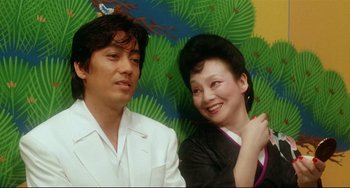 Movie still from “Mishima: A Life in Four Chapters” (1985), directed by Paul Schrader – A man and a woman posing for a picture; Close Up shot, Low angle