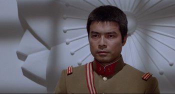 Movie still from “Mishima: A Life in Four Chapters” (1985), directed by Paul Schrader – A man in a military uniform stands in front of an umbrella; Close Up shot, Low angle