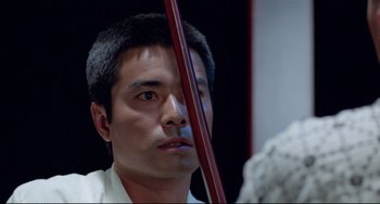 Movie still from “Mishima: A Life in Four Chapters” (1985), directed by Paul Schrader – A person looking at a mirror; Close Up shot, Over the shoulder angle