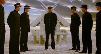 Movie still from “Mishima: A Life in Four Chapters” (1985), directed by Paul Schrader – A group of men standing next to each other in front of a building; Wide shot, Low angle