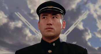 Movie still from “Mishima: A Life in Four Chapters” (1985), directed by Paul Schrader – A person wearing a uniform; Close Up shot, Low angle