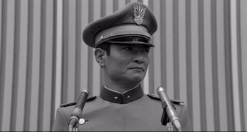 Movie still from “Mishima: A Life in Four Chapters” (1985), directed by Paul Schrader – A black and white photo of a man in a military uniform with two microphones; Close Up shot, Low angle