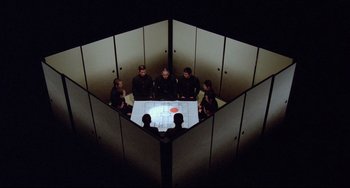 Movie still from “Mishima: A Life in Four Chapters” (1985), directed by Paul Schrader – A group of people sitting around a table in a room; Extreme Wide shot, Overhead angle