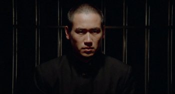 Movie still from “Mishima: A Life in Four Chapters” (1985), directed by Paul Schrader – A person wearing a black shirt; Close Up shot, Low angle