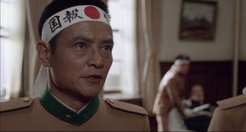 Movie still from “Mishima: A Life in Four Chapters” (1985), directed by Paul Schrader – A man in a military uniform wearing a headband; Close Up shot, Low angle