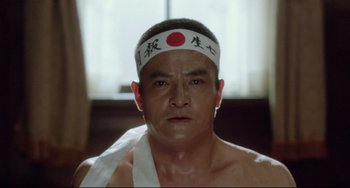Movie still from “Mishima: A Life in Four Chapters” (1985), directed by Paul Schrader – A person wearing a headband; Close Up shot, Low angle