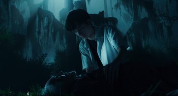 Movie still from “Miss Peregrine's Home for Peculiar Children” (2016), directed by Tim Burton – A young man in a white dress shirt and tie is holding a corpse; Medium shot, Low angle