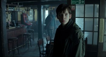 Movie still from “Miss Peregrine's Home for Peculiar Children” (2016), directed by Tim Burton – A young man standing in a room with chairs and tables; Medium shot, Over the shoulder angle