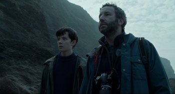 Movie still from “Miss Peregrine's Home for Peculiar Children” (2016), directed by Tim Burton – A man and a young boy standing next to each other on top of a hill; Medium shot, Low angle