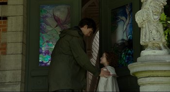 Movie still from “Miss Peregrine's Home for Peculiar Children” (2016), directed by Tim Burton – A man and a girl are standing in front of stained glass windows; Medium shot, Over the shoulder angle