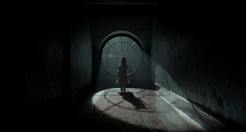 Movie still from “Miss Peregrine's Home for Peculiar Children” (2016), directed by Tim Burton – A little girl is standing in front of a round window; Wide shot, High angle