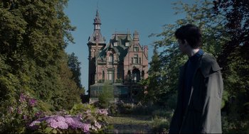 Movie still from “Miss Peregrine's Home for Peculiar Children” (2016), directed by Tim Burton – A man standing in front of an old mansion; Wide shot, Low angle