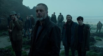 Movie still from “Miss Peregrine's Home for Peculiar Children” (2016), directed by Tim Burton – A group of people standing on top of a grass covered hill; Medium shot, Low angle