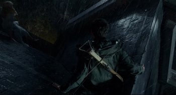 Movie still from “Miss Peregrine's Home for Peculiar Children” (2016), directed by Tim Burton – A man in a green jacket holding an arrow in the rain; Wide shot, Overhead angle