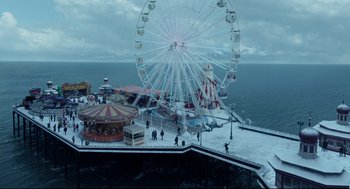 Movie still from “Miss Peregrine's Home for Peculiar Children” (2016), directed by Tim Burton – A large ferris wheel on the beach with people standing around it; Extreme Wide shot, High angle