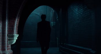 Movie still from “Miss Peregrine's Home for Peculiar Children” (2016), directed by Tim Burton – A man in a black suit walking in a dark alley way; Wide shot, Low angle