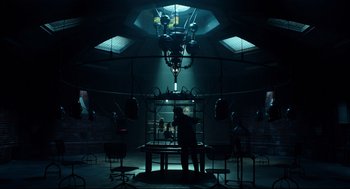 Movie still from “Miss Peregrine's Home for Peculiar Children” (2016), directed by Tim Burton – A person is sitting in front of a cage in a dark room; Wide shot, Low angle