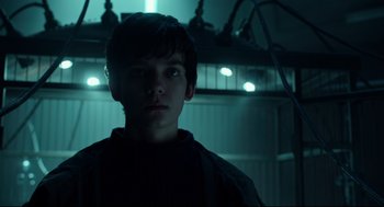 Movie still from “Miss Peregrine's Home for Peculiar Children” (2016), directed by Tim Burton – A young boy is standing in a dark room; Close Up shot, Low angle