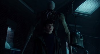 Movie still from “Miss Peregrine's Home for Peculiar Children” (2016), directed by Tim Burton – A man standing next to an octopus in a dark room; Medium shot, Low angle